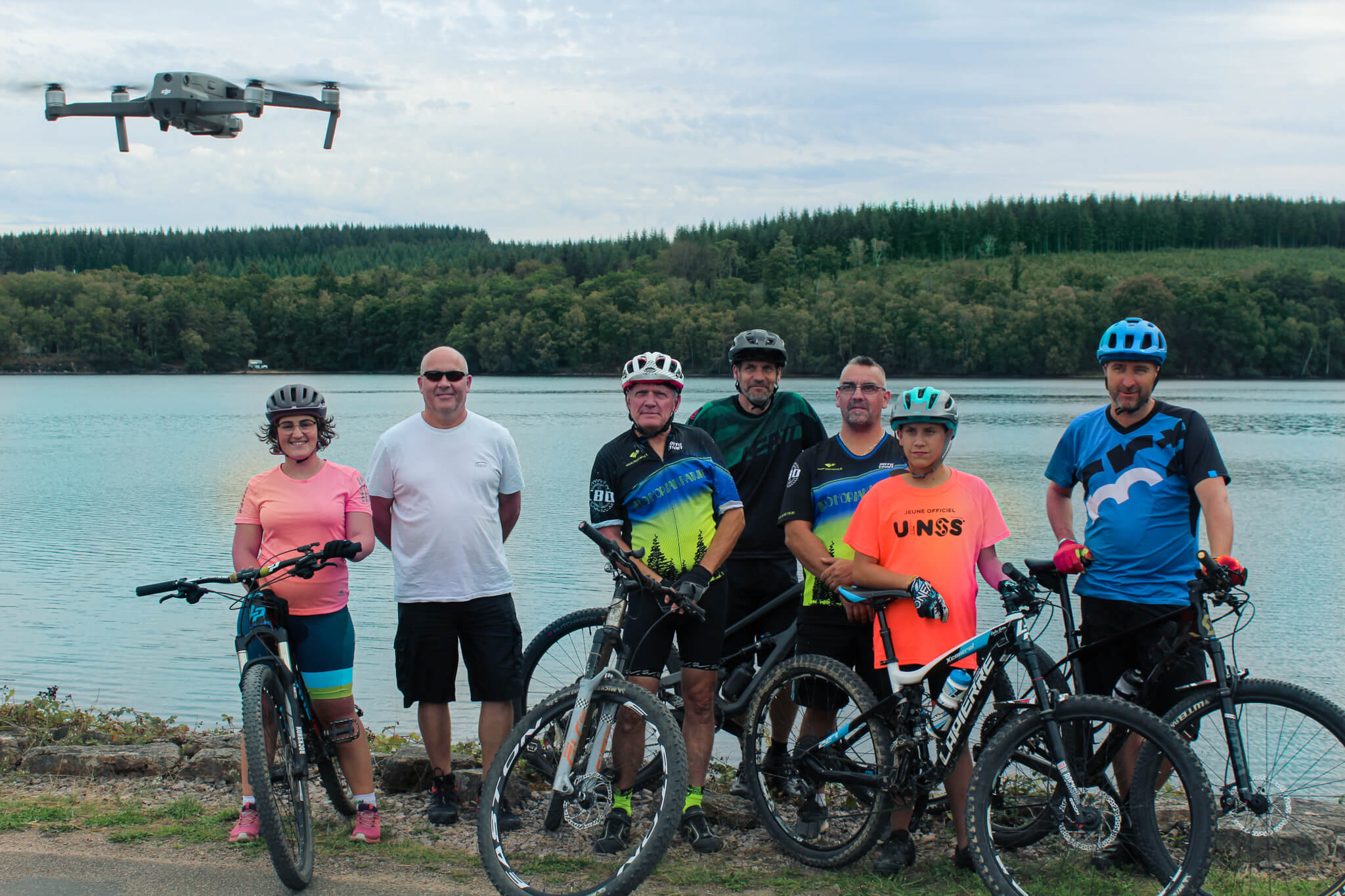 Photographie d'un groupe de vététistes regardant un drone s'élever'